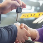 Used car seller hands the keys to a buyer while shaking hands